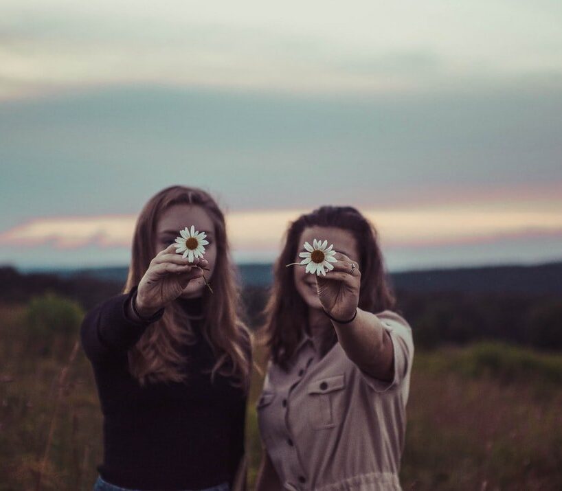 Women holding flowers together in the field